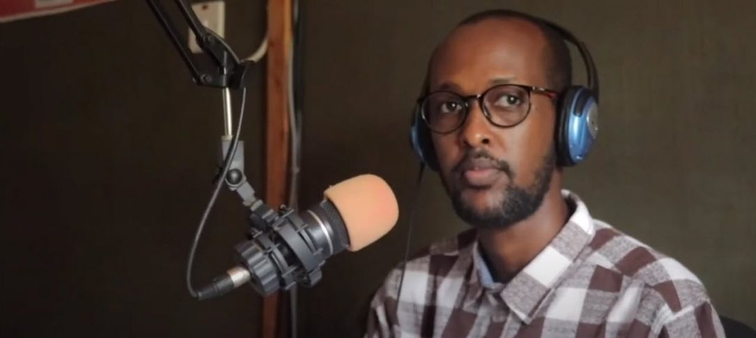 A man wearing headphones sits in front of a microphone