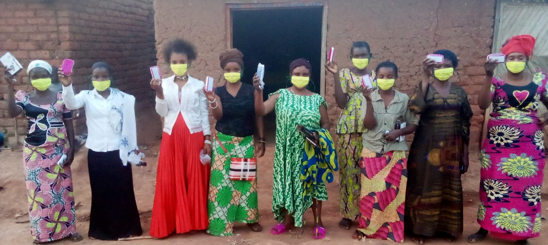 A group of women wearing face masks hold up cards