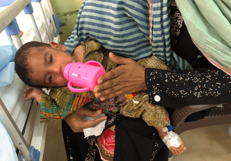 Picture of a child drinking clean water at a health center in Pakistan.